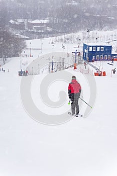 View down slope, skiing, skier back view. Winter sport