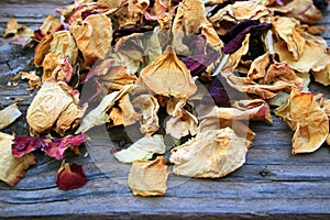 DRY ROSE PETALS ON A WOODEN BOARD