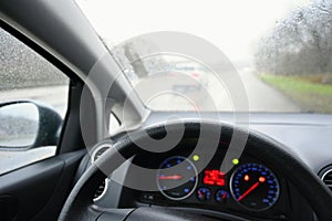 View from the driver - car interior with steering wheel and dashboard. Winter bad rainy weather and dangerous driving on the road