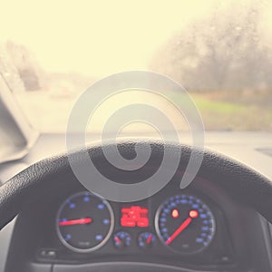 View from the driver - car interior with steering wheel and dashboard. Winter bad rainy weather and dangerous driving on the road