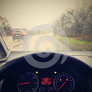 View from the driver - car interior with steering wheel and dashboard. Winter bad rainy weather and dangerous driving on the road