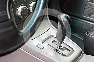 View from the driver`s seat of the gear shift lever in a car with an automatic transmission and climate control panel