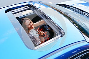 View of a driving woman through sunroof