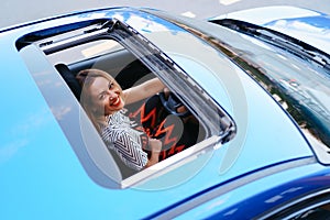 View of a driving woman through sunroof