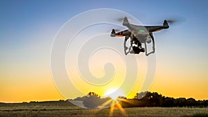 View of drone flying with digital camera over a field with sunset