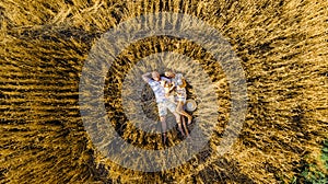 View from drone to family lying among wheat field with baby