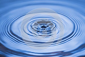 View of drops making circles on blue water surface isolated on background