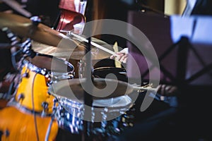 View of drum set kit on a stage during jazz rock show performance, with band performing in the background, drummer point of view