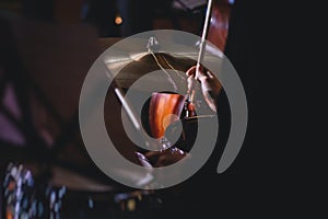 View of drum set kit on a stage during jazz rock show performance, with band performing in the background, drummer point of view