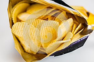 View of dry crispy fried corrugated potato chips in open bag