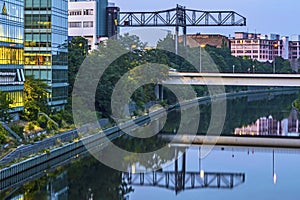 View at dusk along the Teltow Canal. You can see office buildings, at the top of the photo an industrial crane and a road bridge.