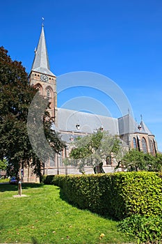View on dutch neo gothic church from 18th century with green trees against blue summer sky - Baak, Sint Martinuskerk, Netherlands