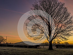 A view through the early morning mist towards the Wrekin hill, UK with a glowing sky