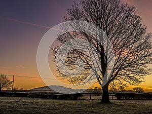 A view through the early morning mist towards the Wrekin hill, UK with a glowing sky photo