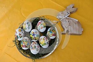 View on easter eggs and a wooden easter bunny on a yellow tablecloth