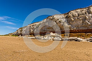 A view eastward along the white, red and orange stratified chalk cliffs of Old Hunstanton, Norfolk, UK