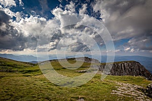 View from the edge of Rax plateau, with green, grassy meadow and blue cloudy sky