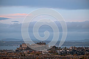 View of Edinburgh city centre and castle with the sea in the background and a flying plane in the sky