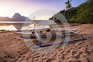 View of El Nido bay with local banca boat in front at low tide, picturesque scenery in the afternoon, Palawan