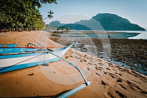 View of El Nido bay with local banca boat in front at low tide, picturesque scenery in the afternoon, Palawan