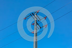 View of electricity pole and power lines with blue sky as background