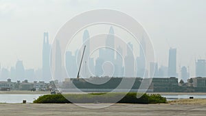 View from the embankment on the city sky scrapers in fog. Action. Tall buildings in a morning haze.