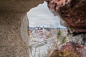 View through an embrasure in the castle wall of the fortress Feste Oberhaus near the three rivers city Passau with view on the cit