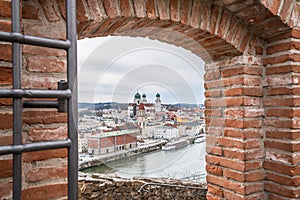 View through an embrasure in the castle wall of the fortress Feste Oberhaus near the three rivers city Passau with view on the cit