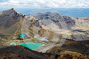 View of Emerald lakes from Tongariro Alpine Crossing hike with clouds above, North Island, New Zealand