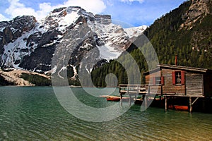 View of the emerald smooth surface of Lago di Braies lake and snow capped mountains in Dolomite Alps, Italy photo