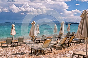 View of empty beach - white deck chairs and umbrellas near sea water