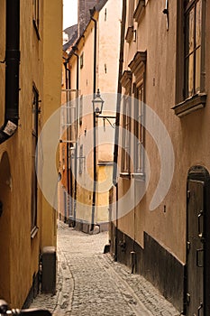 View of an empty, cobble street, alley between city buildings abroad in Stockholm, Gamla Stan. Narrow cobbled stone road