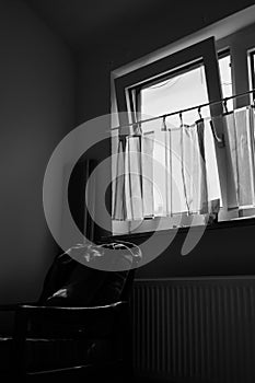 View of empty and dark room with bright sunlight through glass window with curtain