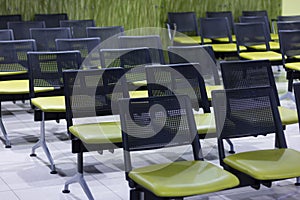 View of empty hospital waiting room full of green chairs rows