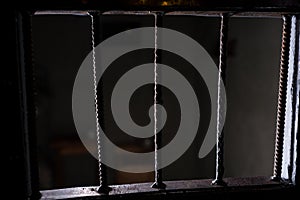 View of the empty jail cell through the bars of the doors