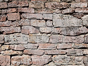 View of empty, old white, pink and grey brick wall background with copy space. A deteriorating old brick wall outdoors in sunlight