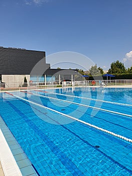 View of empty outdoor pool with swimming lanes on summer sunnyday