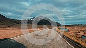 View of empty road leading towards mountain range in Iceland.