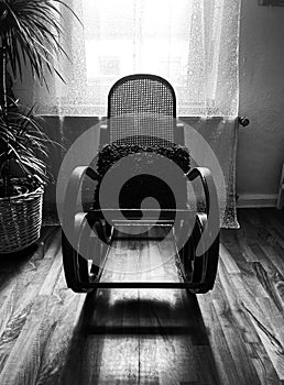 View on empty rocking chair in living room with shadow from backlight of window - grieve and loss of loved person concept