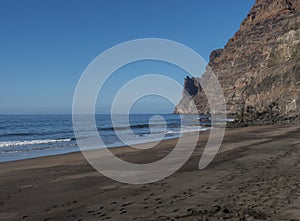 View of empty sand beach Playa de Guigui with rocky cliffs in west part of the Gran Canaria island, accessible only on