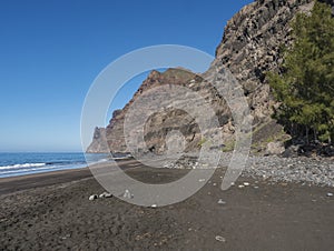 View of empty sand beach Playa de Guigui with rocky cliffs in west part of the Gran Canaria island, accessible only on