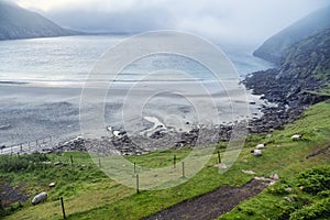 View on an empty sandy beach, fog over ocean and mountains in the background. Keem bay, county Mayo, Ireland. Popular travel area