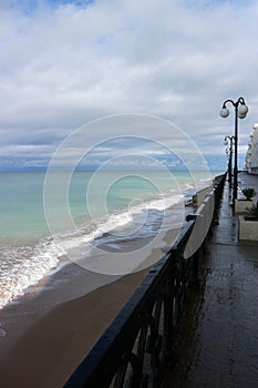 view of empty seaside promenade and sand beach in stormy autumn day