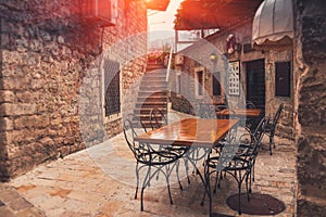 View of empty terrace of open-air cafe with tables and chairs in old town of Budva. Montenegro.