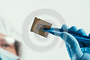 View of engineer holding computer microchip with tweezers