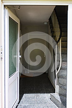 View of entrance of cheap apartment with door open and staircase in summer