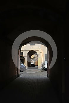 Dark arch and courtyard with parked cars