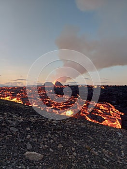 View of an erupting volcano surrounded by glowing lava. Iceland