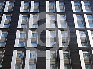 facade of a large black and white modern commercial building with repeating windows and geometric panels