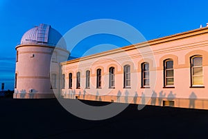 View of the facade of the main building of the historical Lick Observatory (completed in 1888) at sunset; visitors ' shadows